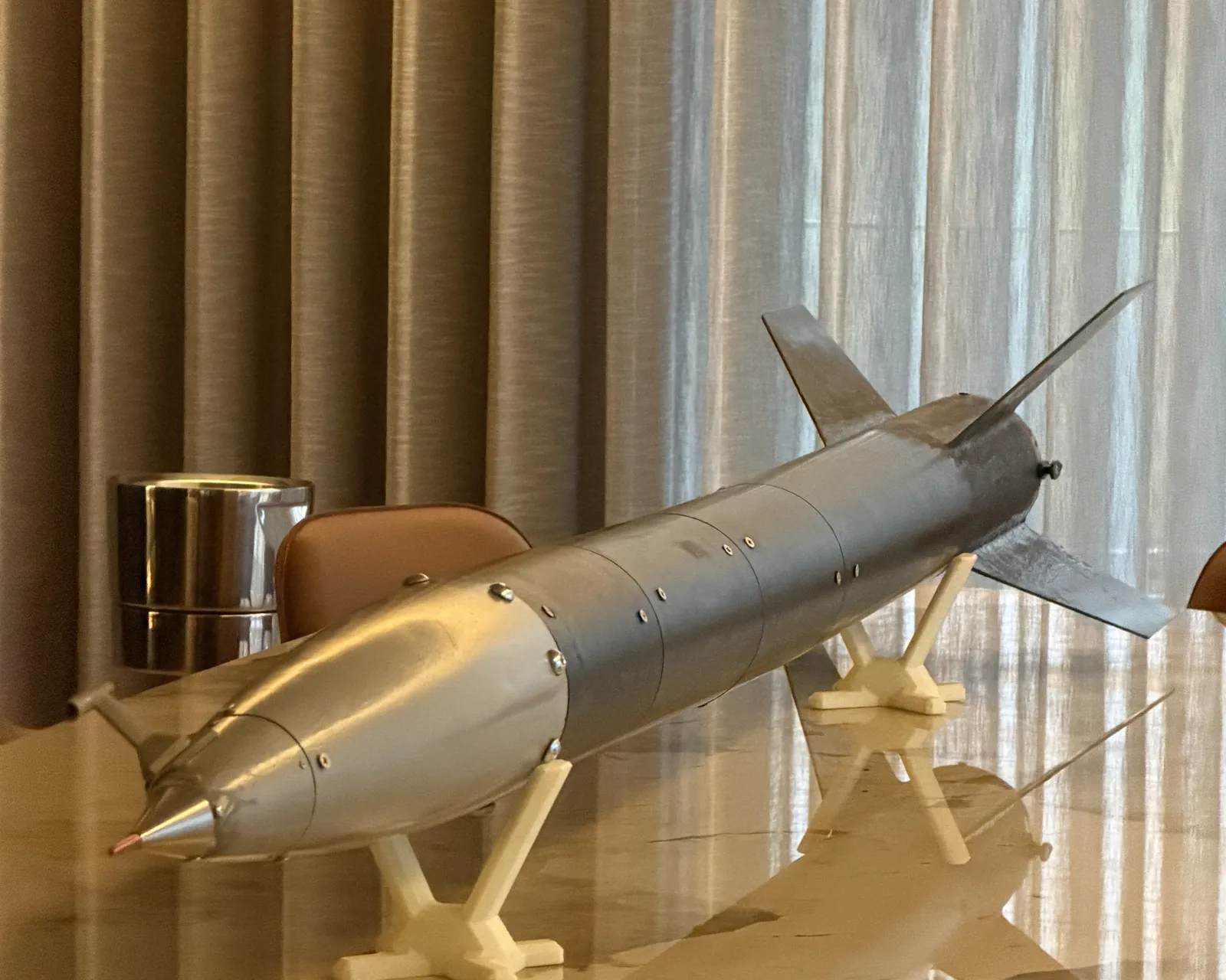 Lynxrocket V5 horizontal on printed cradles: ogive nose cone with its machined tip and pitot-static probe in the foreground, bolted body sections, and the fin can beyond
